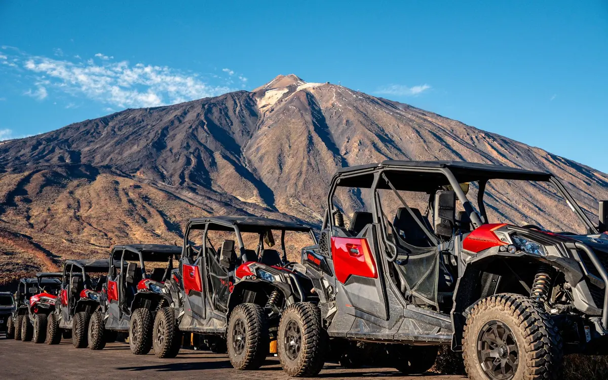 A convoy of buggies climbing a track on the flanks of the mountain