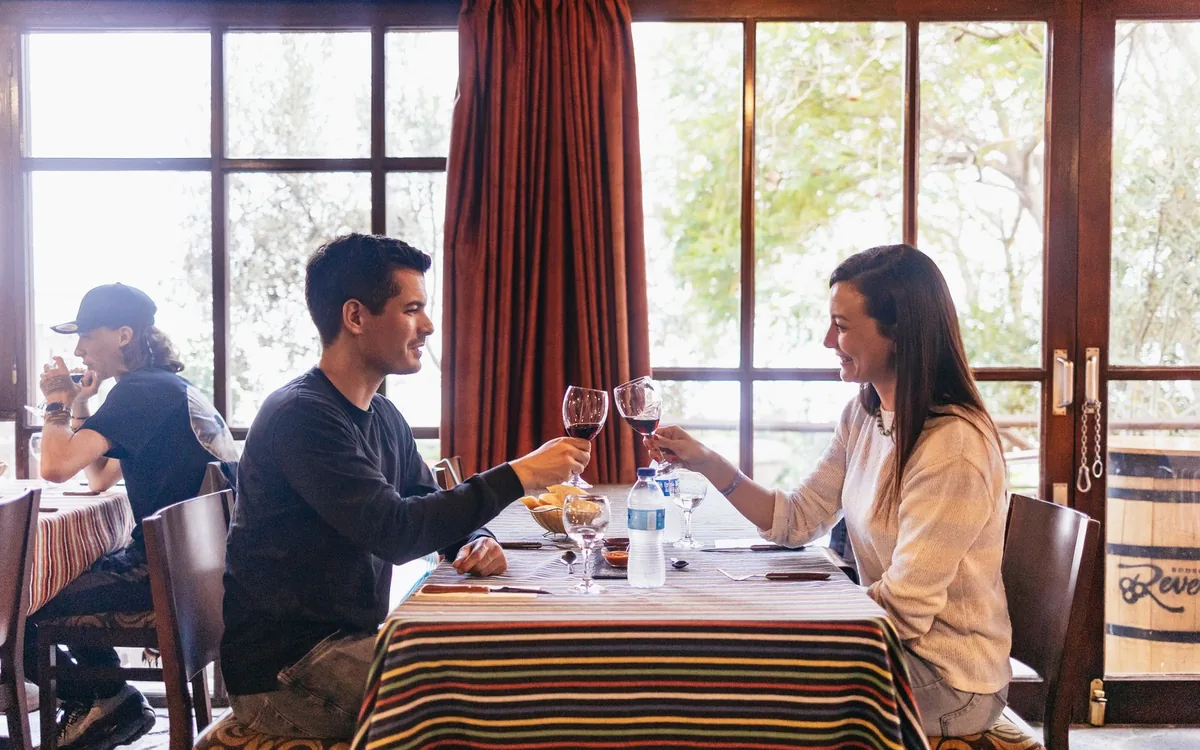 A couple at a laid dinner table beside a window as the light goes outside