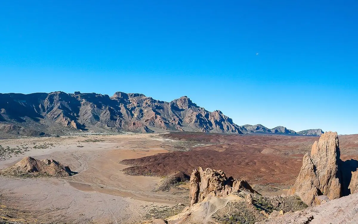 A wide dark lava plain running out to a ridge under a deep blue sky