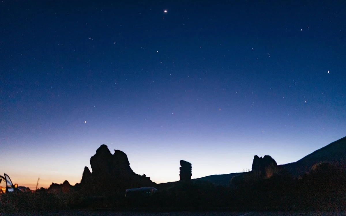 Deep blue dusk sky with the first stars appearing above dark rock formations in the park