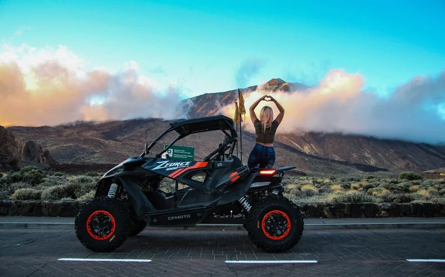 A black buggy on a road through the park with the Teide cone behind it
