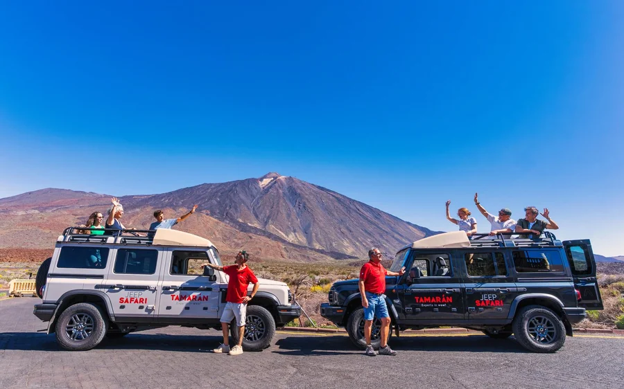 White off-road jeeps parked on gravel with their group standing beside them