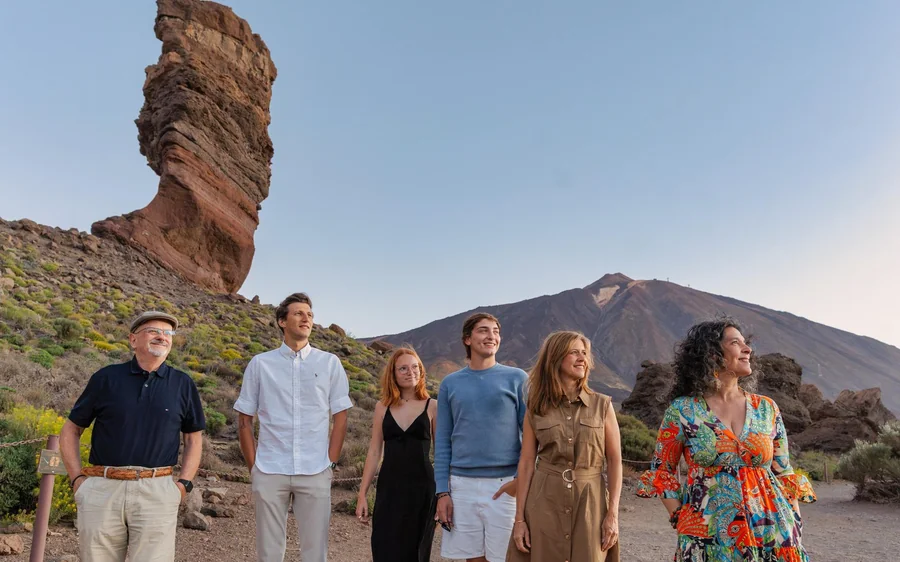 A group of travellers standing together in front of the rock pillar and the mountain