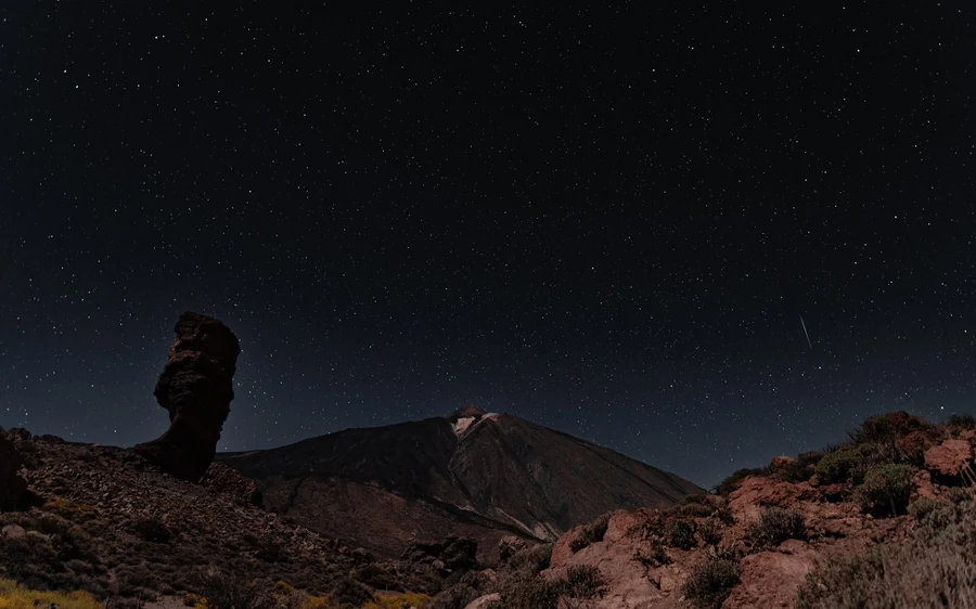 The dark silhouette of the rock pillar against the last light of the sky