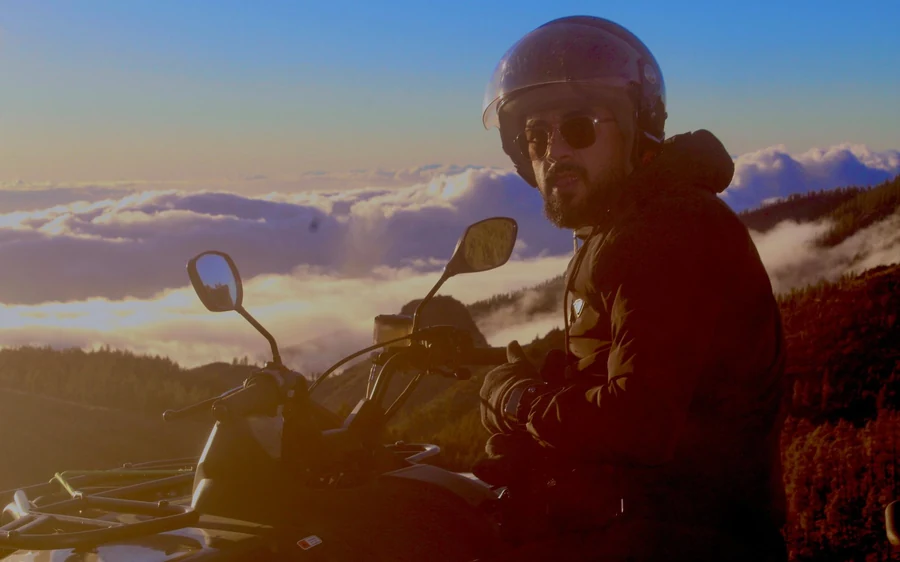 A helmeted rider on a quad against an orange dusk sky