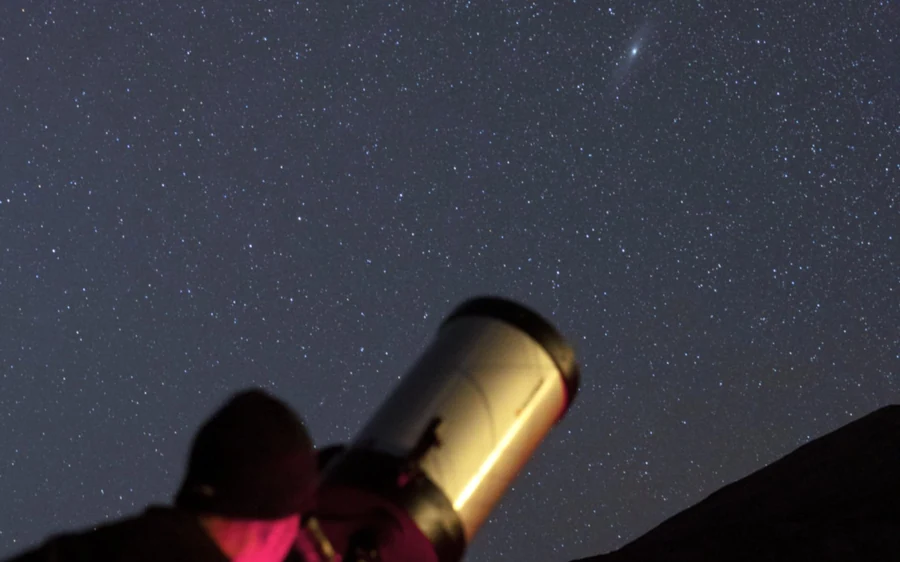The golden tube of a telescope pointed up at a dark sky