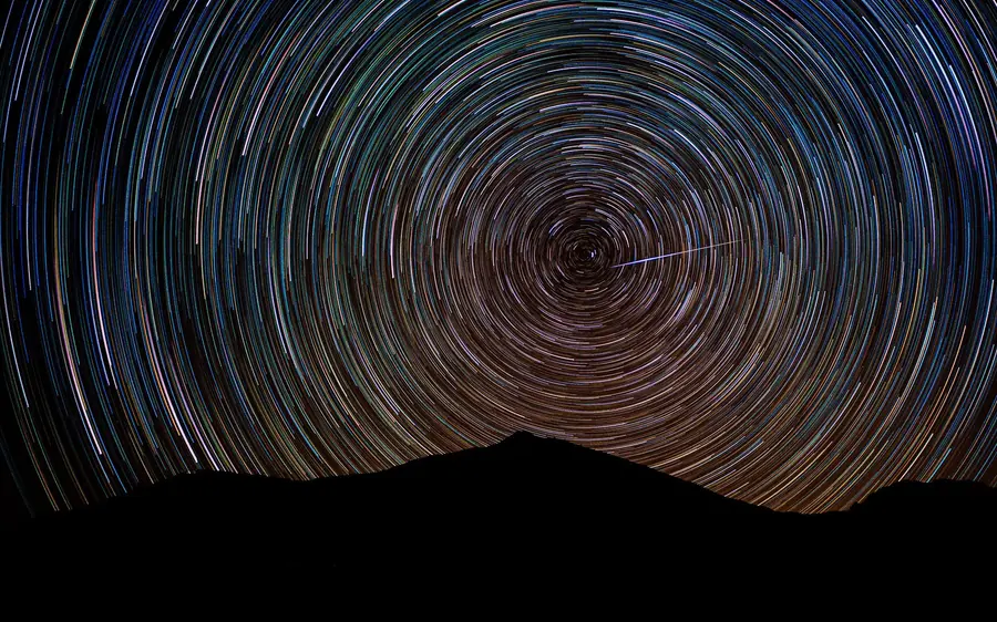 Star trails circling above the dark ridge of the volcano